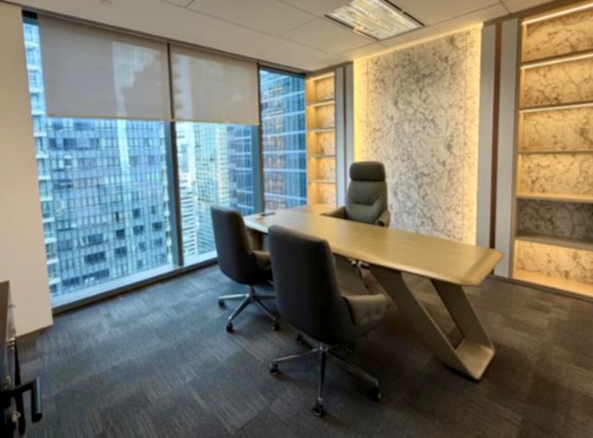 Modern office with a wooden desk, three chairs, large windows showing city buildings, and illuminated wall shelves.