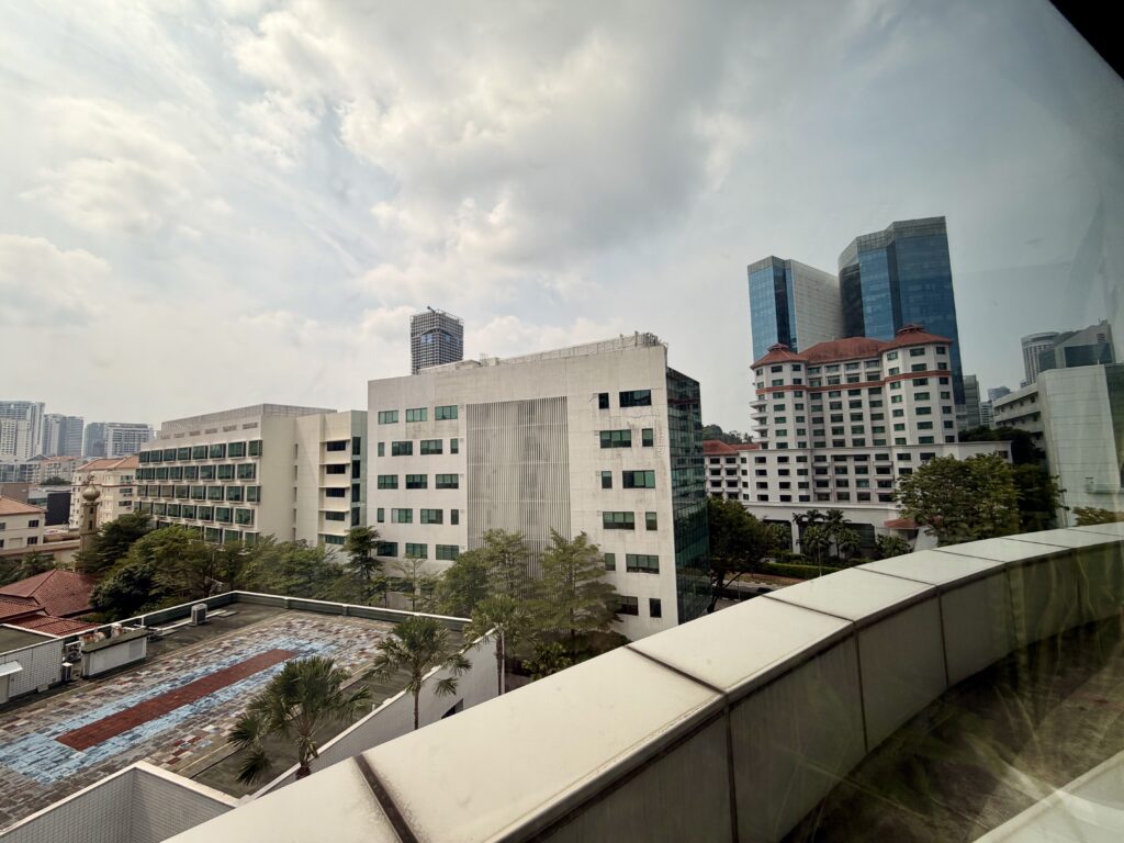 View of multiple office and residential buildings in a city with cloudy skies, seen from a balcony.
