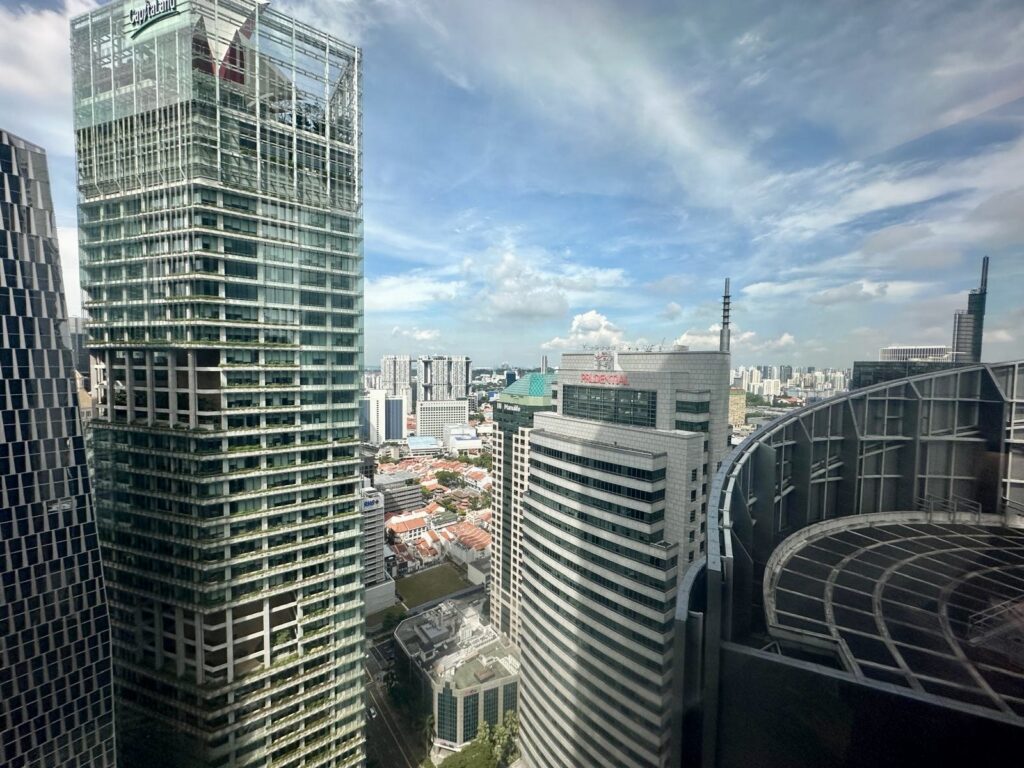 High-angle view of the Singapore skyline featuring modern skyscrapers, including the CapitaLand and Prudential buildings, under a blue sky.