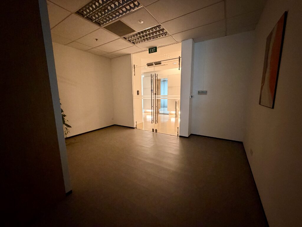 An empty room leading to a glass door marked with an exit sign.