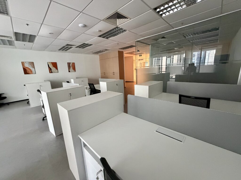 Modern office space with white desks, privacy partitions, and three abstract wall prints.