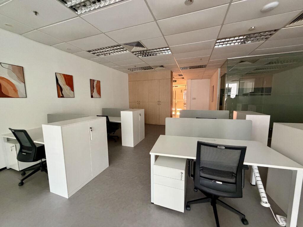Modern office space with white desks, black mesh chairs, and storage cupboards.