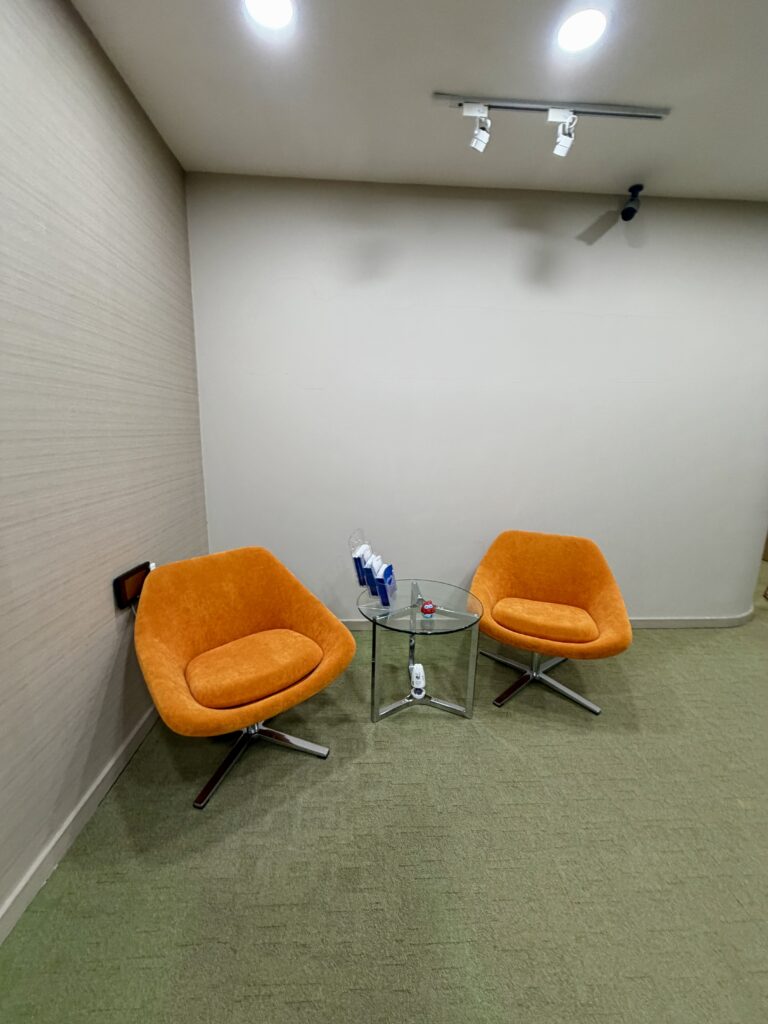 Two orange swivel chairs face a small glass side table in a corner.