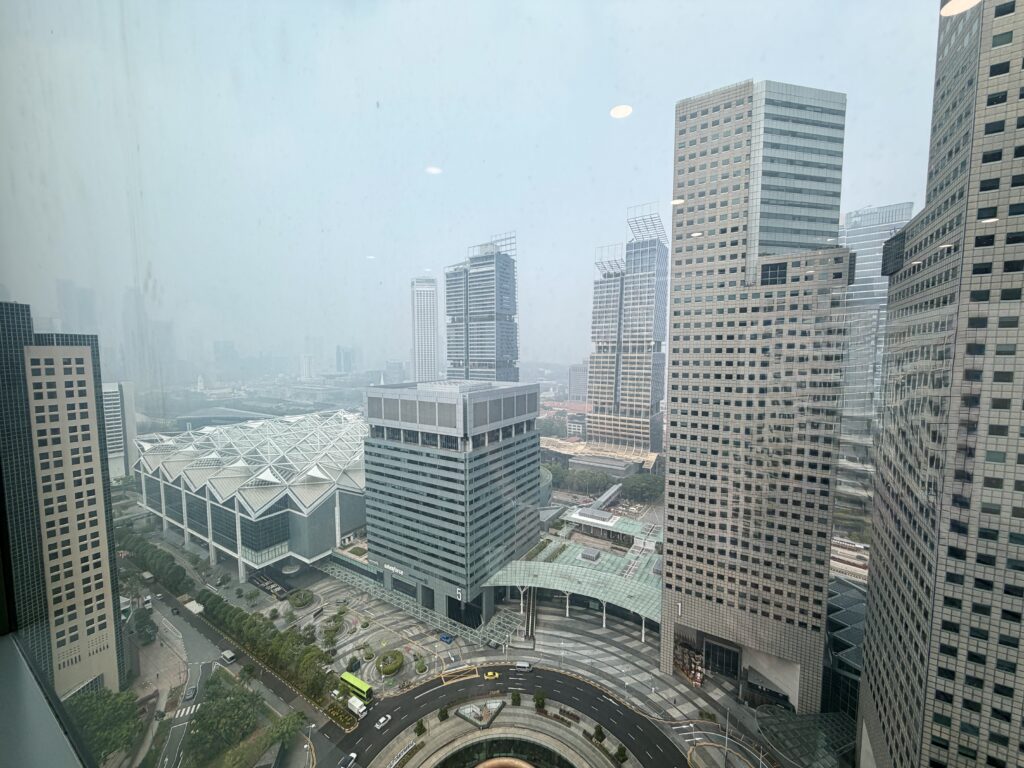 High-angle view of a city skyline with skyscrapers, a domed building, and a curved road in the foreground.